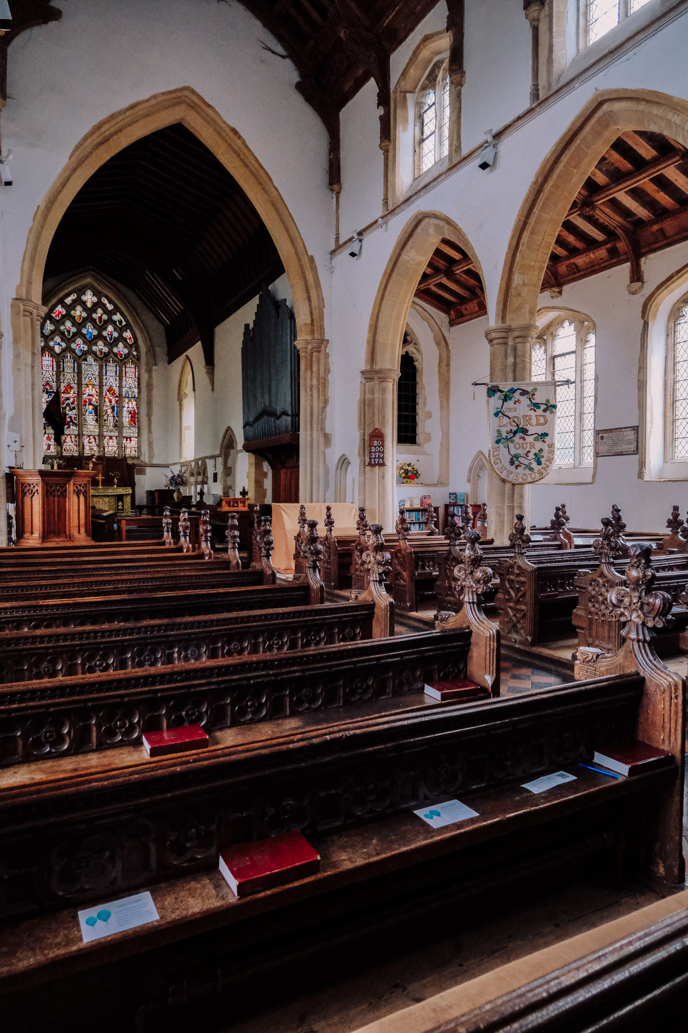 Interior of a church featuring wooden pews, stained glass windows, and a decorative altar.