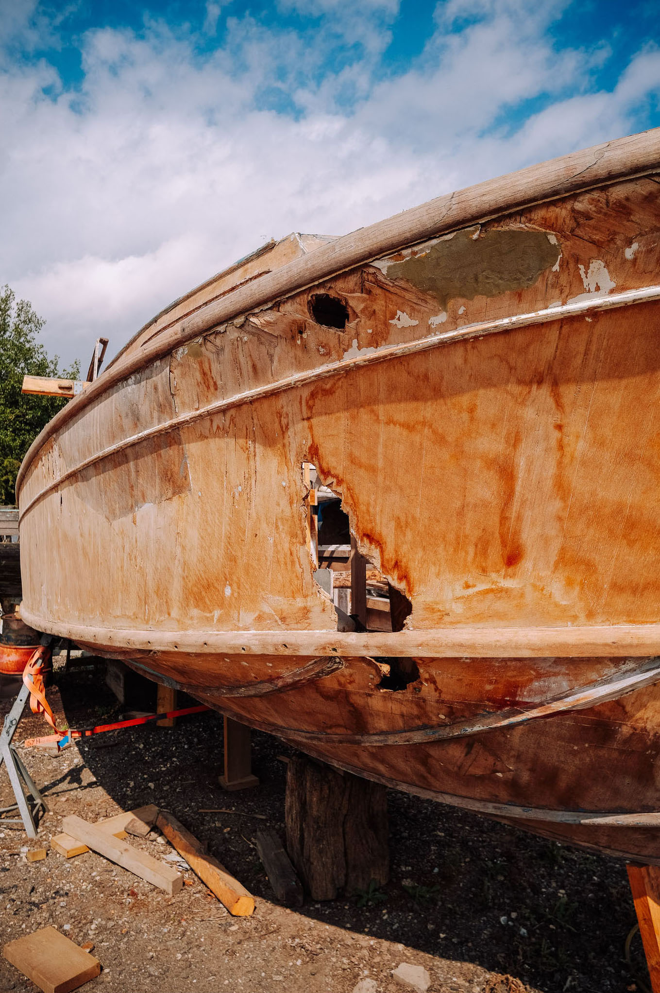 Close-up view of a wooden boat in need of repair, showing significant damage and peeling paint.